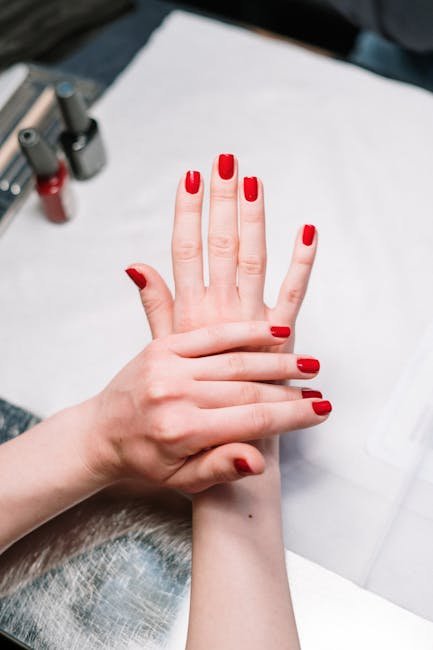 pexels-photo-3997386-3997386 Close-up of elegant red nail polish on hands in a salon setting, showcasing modern manicure art.