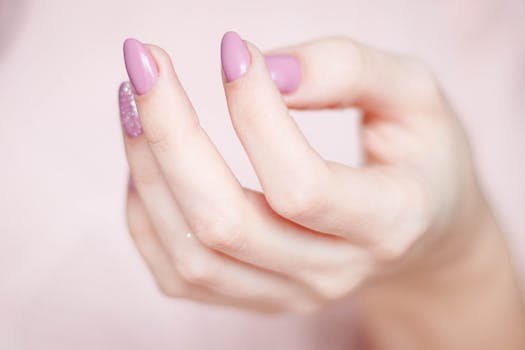 pexels-photo-939835-939835 A close-up of a woman's hand showing a stylish pink and glittery manicure.