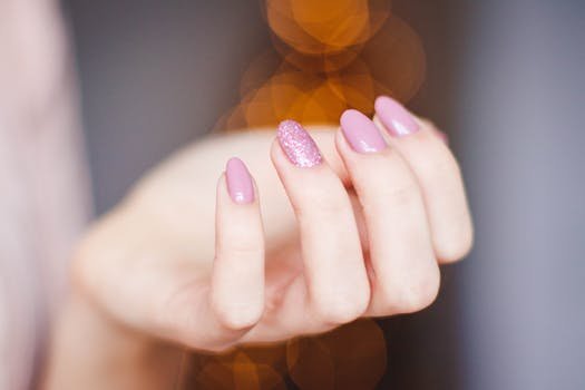pexels-photo-939836-939836 A close-up of a woman's hand displaying a stylish pink glitter manicure, highlighting nail art details.